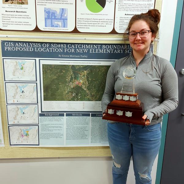 Student holding the Carto Cup trophy in front of her research poster.