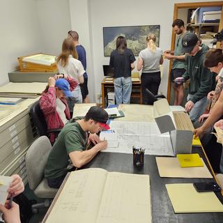students gathered around a table studying various old documents