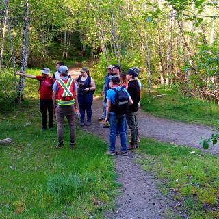 students standing in the woods at a fork in the trail listening to an instructor give directions