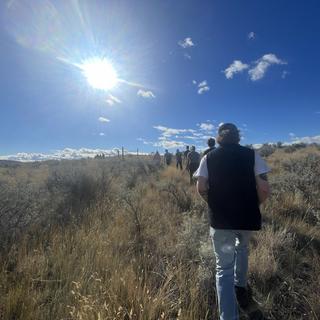 students move through a grassland towards the sun