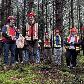 students standing, some laughing, in the forest