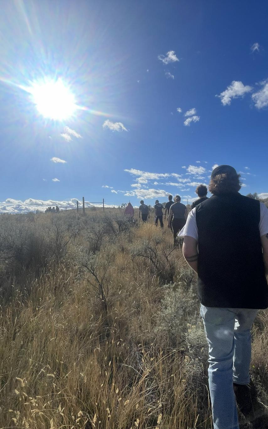students move through a grassland towards the sun