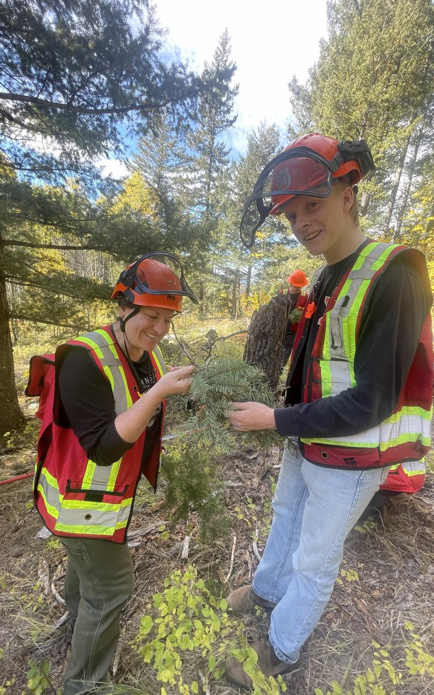 smiling woman and man in high vis looking at tree foliage in the forest